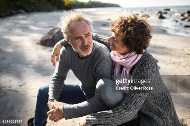 affectionate mature couple on the beach - in den fünfzigern stock-fotos und bilder