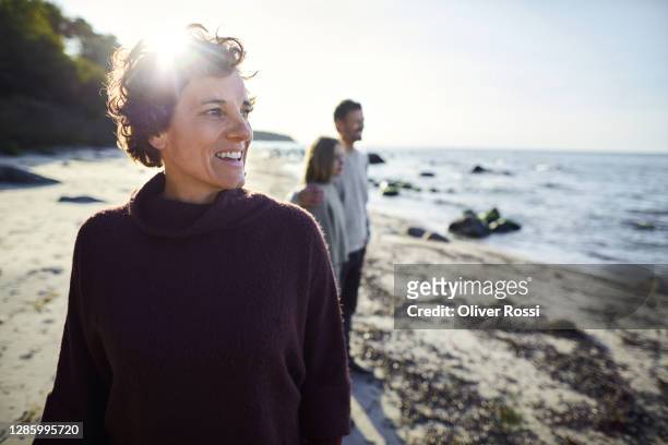 smiling woman on the beach with family in background - group sea stock pictures, royalty-free photos & images