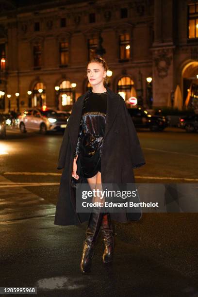 Gaia Weiss wears a black long coat, a black shiny sequined dress, black leather knee high boots, outside Etam, during Paris Fashion Week - Womenswear...