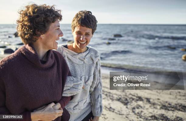 happy mature woman and young woman on the beach - mature woman daughter stock pictures, royalty-free photos & images