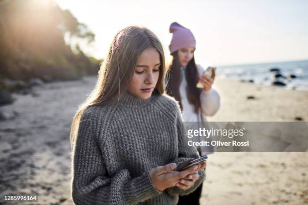 girlusing smartphone on the beach - junge 13 jahre oberkörper strand stock-fotos und bilder