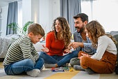 Cheerful parents playing board game with their children.