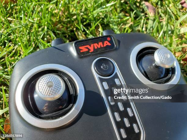 Close-up of a drone controller on a grass lawn displaying the Syma logo in Central Park in San Ramon, California, USA, November 7, 2020.