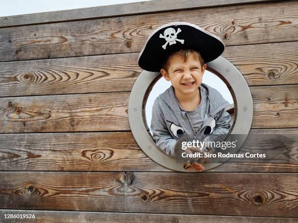 little boy wearing a pirate hat and smiling inside a pirate ship and holding a sword - pirate hat stock pictures, royalty-free photos & images