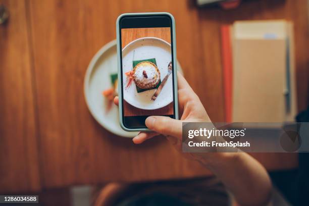 ソーシャルメディアに投稿するために、彼女のおいしい見た目のカボチャスパイスのスナップショットを撮る匿名の若い女性の手 - instagram ストックフォトと画像