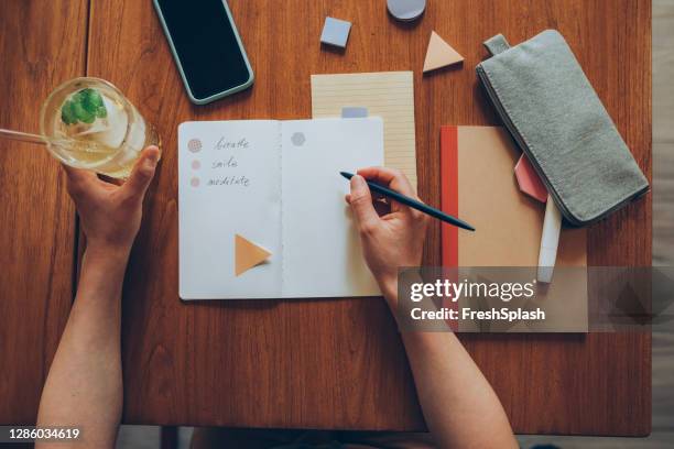 anonymous female student writing motivational notes in her notebook while having a glass of lemonade in a cafe - bullet points stock pictures, royalty-free photos & images