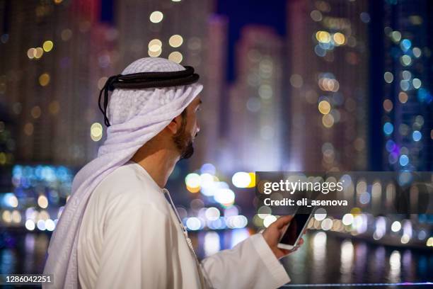 emirati man on the phone at the night dubai marina - united arab emirates night stock pictures, royalty-free photos & images