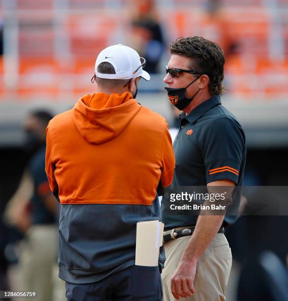 Head coach Mike Gundy of the Oklahoma State Cowboys talks with Head coach Tom Herman of the Texas Longhorns before their game at Boone Pickens...