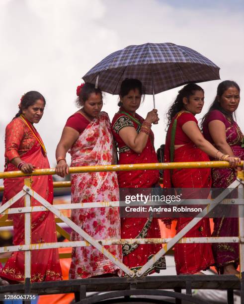 women waiting under an umbrella in line at hindu teej festival pashupatinath temple, kathmandu, nepal - teeji festival stock pictures, royalty-free photos & images