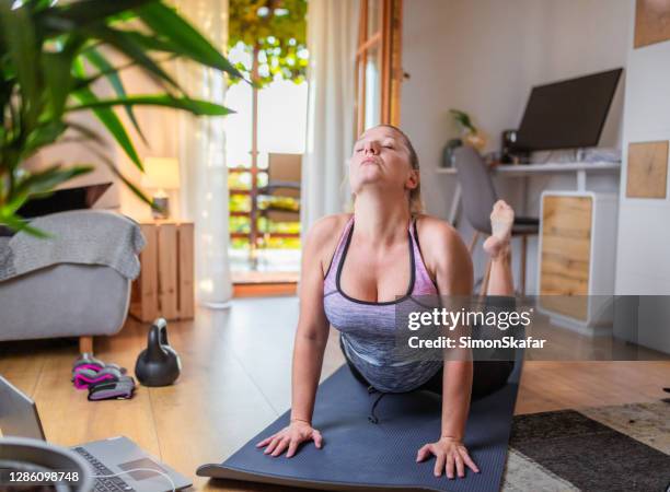 woman doing yoga in the living room - closed laptop stock pictures, royalty-free photos & images