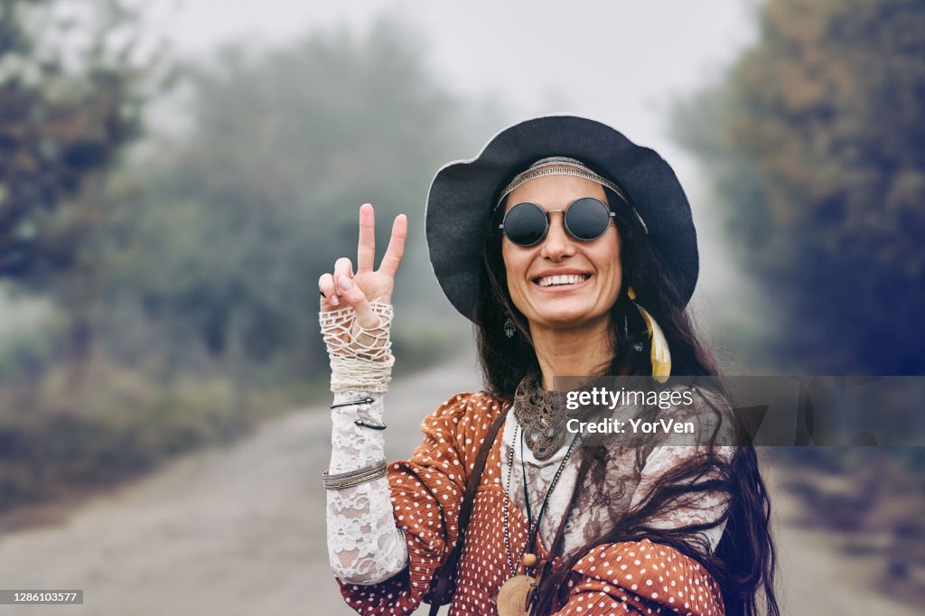 Smiling hippie woman giving peace sign