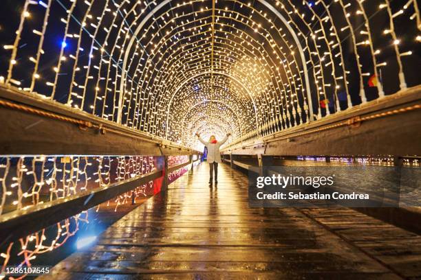 girl admiring the tunnel with holiday lights, public lighting for the christmas and new year holidays - city year stock-fotos und bilder