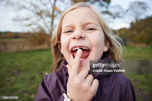 cute blond girl showing new tooth in garden - vrouw spleetje tanden stockfoto's en -beelden