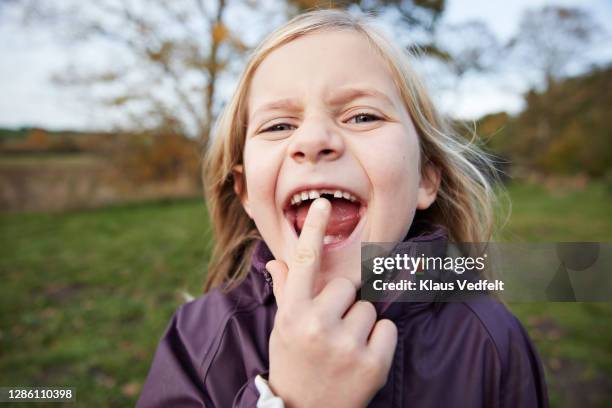 cute blond girl showing new tooth in garden - losing virginity - fotografias e filmes do acervo