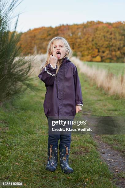 girl showing middle finger while standing at park - kid middle finger stock-fotos und bilder