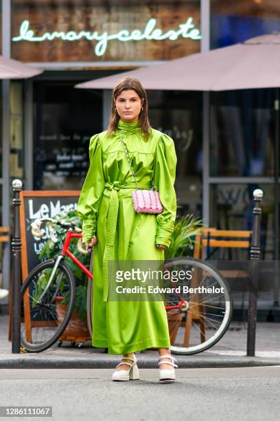 Alice Violier wears a green silky lustrous turtleneck dress with puff long sleeves, a pink mesh bag, white shoes, outside Paco Rabanne, during Paris...