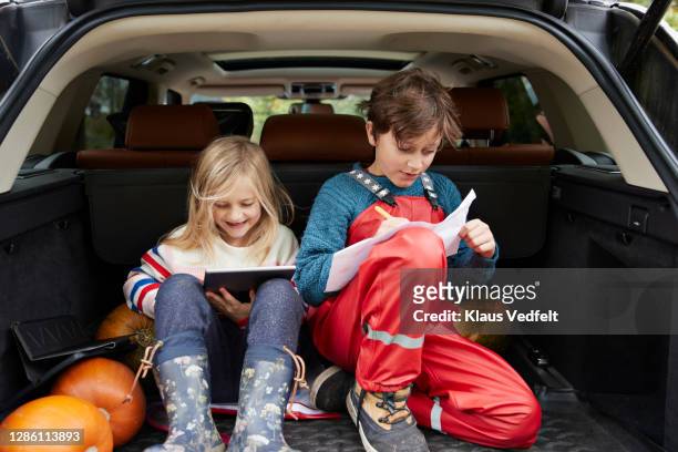 siblings enjoying autumn while sitting in car trunk - travel writer stock pictures, royalty-free photos & images