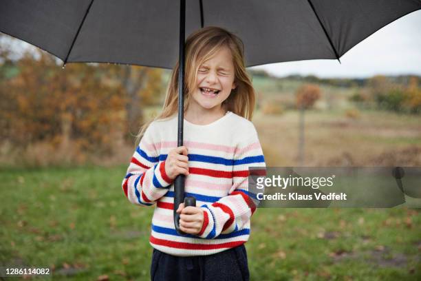 cute girl with eyes closed holding umbrella - standing in the rain girl stock pictures, royalty-free photos & images