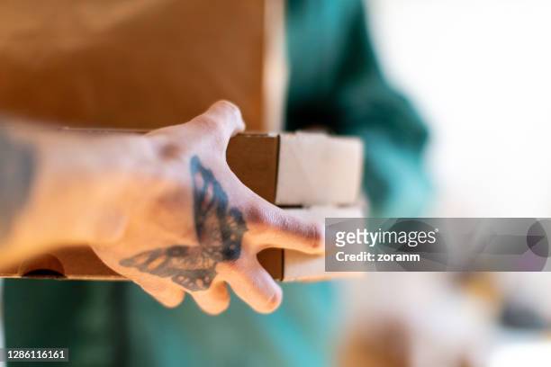 hand with butterfly tattoo taking delivered pizza boxes - butterfly tattoos stock pictures, royalty-free photos & images