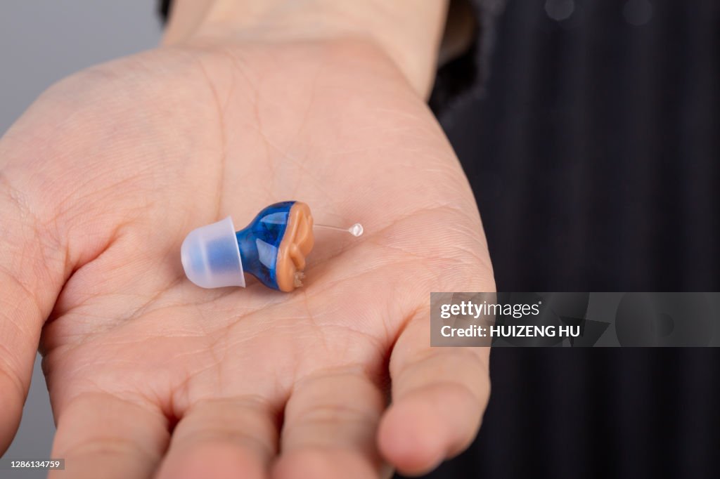 Close-up Of hearing aid on woman palm