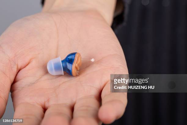 close-up of hearing aid on woman palm - hearing aids stock pictures, royalty-free photos & images