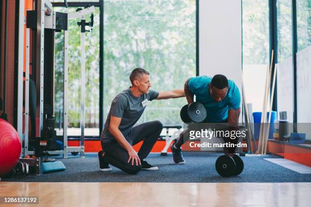 entrenamiento con entrenador personal masculino en el club de salud - instructor de acondicionamiento físico fotografías e imágenes de stock