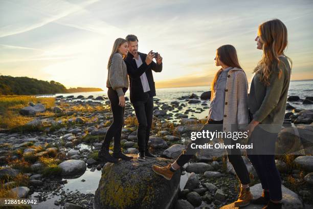 father taking smartphone picture of his family at the sea - young teen girl beach foto e immagini stock