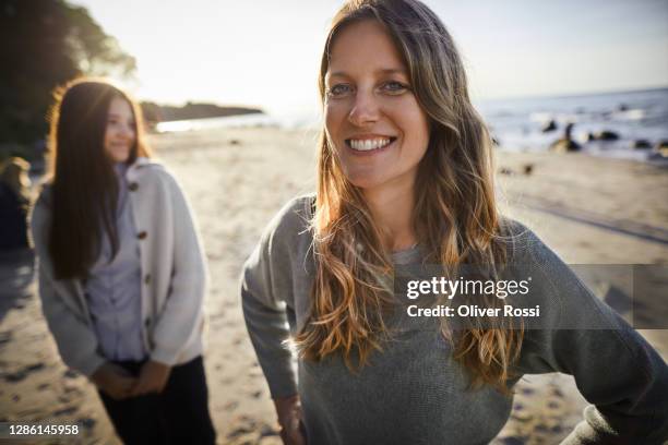 portrait of smiling woman with daughter on the beach - adolescent daughter mother portrait stock-fotos und bilder