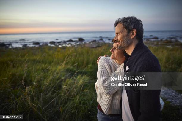 confident couple looking at view at the sea - couple photos et images de collection