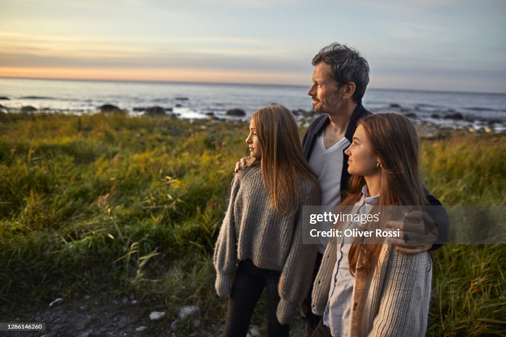 Father with two girls looking at view at the sea