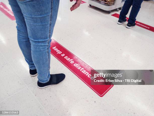 warning banner on the floor asking to keep a safe distance in line - supermarket queue stock pictures, royalty-free photos & images