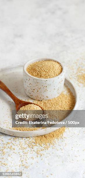 bowl of raw amaranth grain with a spoon - amarant stock pictures, royalty-free photos & images