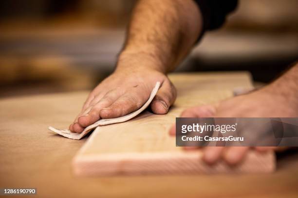 hands of carpenter using sand paper on a plank - sand paper stock pictures, royalty-free photos & images