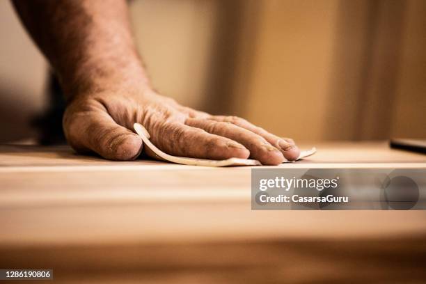 mão de um carpinteiro maduro esfregando madeira com papel de areia - carpenter - fotografias e filmes do acervo