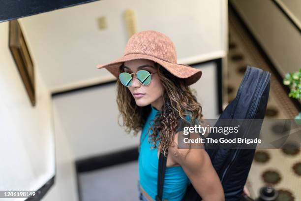 portrait of beautiful woman carrying guitar case at staircase - blues musician stock pictures, royalty-free photos & images