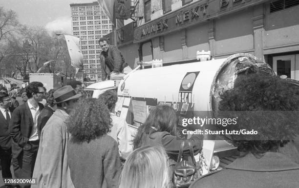 Man sits on the roof of a tanker truck exhibit, on a sunny day, while a crowd reads information panels attached to the tank during the first annual...