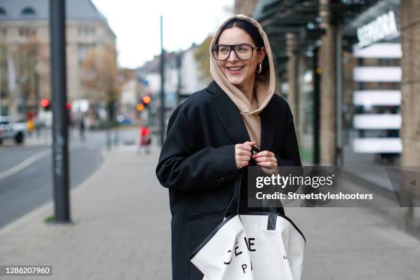 Influencer Maria Barteczko, wearing a black oversized blazer by The Frankie Shop, a beige cotton jogging suit by Tekin, black and white textile tote...