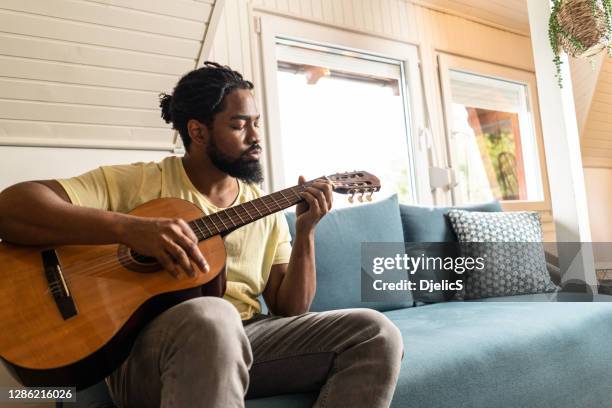 man playing a guitar at home. - tuning stock pictures, royalty-free photos & images