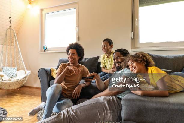 african american family watching tv together at home. - african american watching tv stock pictures, royalty-free photos & images