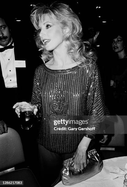 View of American actress Morgan Fairchild , holding a drink, during a TeleRep party at the Waldorf-Astoria hotel, New York, New York, September 28,...