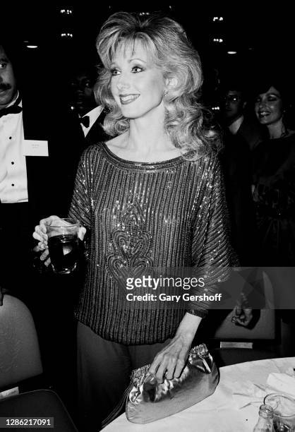 View of American actress Morgan Fairchild , holding a drink, during a TeleRep party at the Waldorf-Astoria hotel, New York, New York, September 28,...