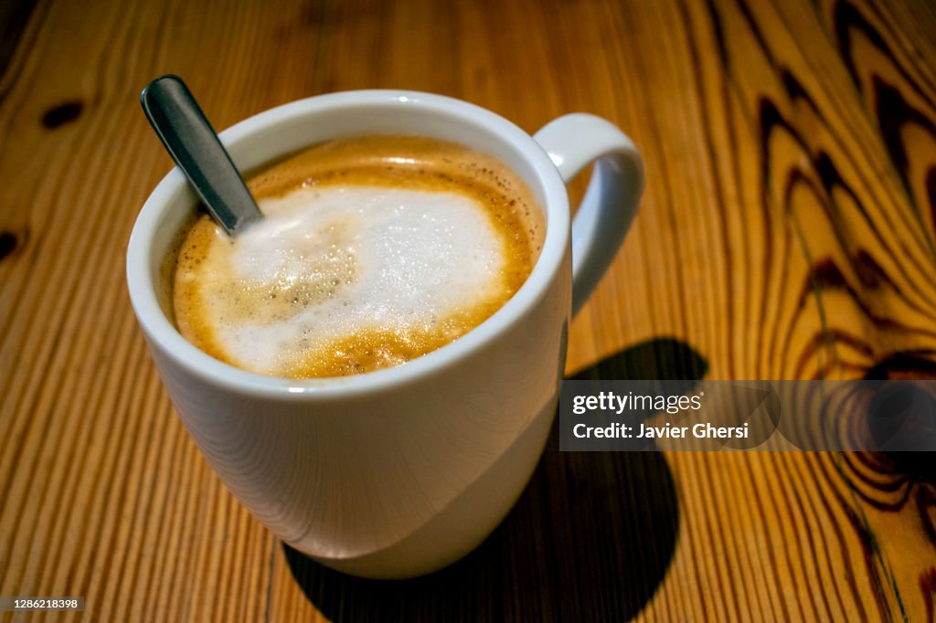 Taza de café con leche sobre mesa de madera