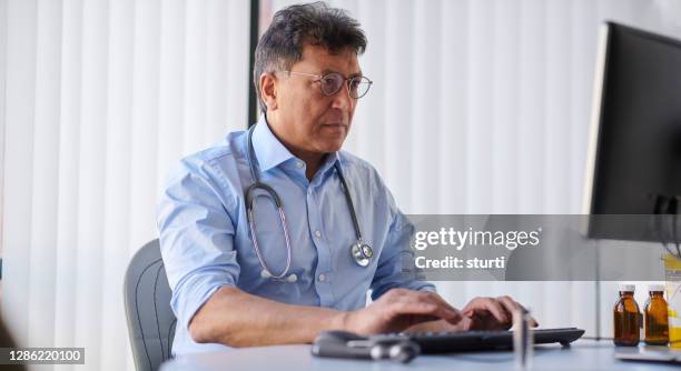 gp escribir carta en el ordenador - médico de cabecera fotografías e imágenes de stock