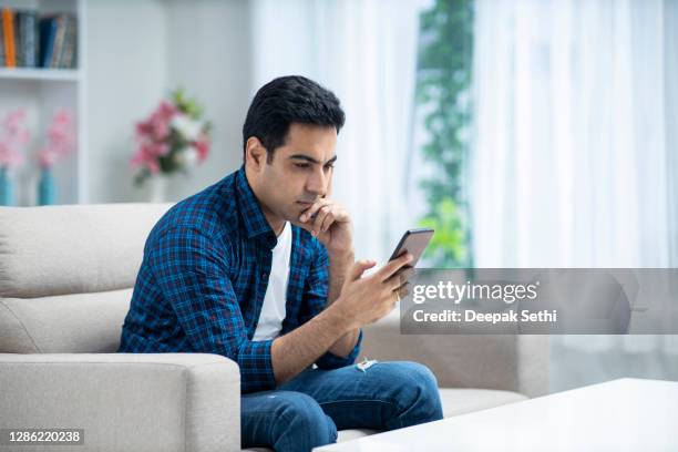 young man at home sofa sitting - stock photo - mobile devices at home stock pictures, royalty-free photos & images