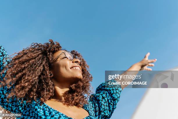 young woman with african roots raising her arms - stock photo - adult sky lady smile stock pictures, royalty-free photos & images