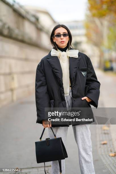 Gabriella Berdugo wears sunglasses from Ralph Lauren, a black puffed winter oversized jacket from Prada, beige organza blouse shirt with Lavallière...