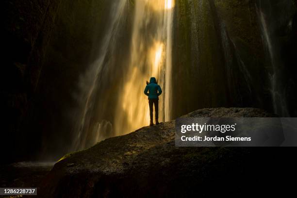 a woman standing under a waterfall in iceland. - behind waterfall stock-fotos und bilder