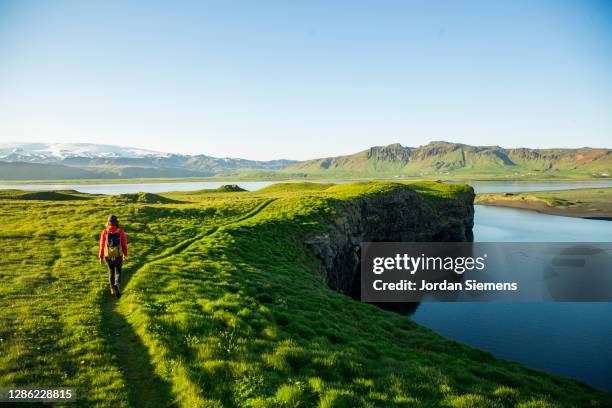 a woman hiking a lush scenic trail along a lagoon in iceland. - reykjavik city stock pictures, royalty-free photos & images
