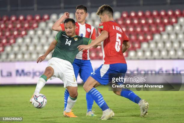 Leonel Justiniano of Bolivia competes for the ball with Richard Sánchez and Gastón Giménez of Paraguay during a match between Paraguay and Bolivia as...
