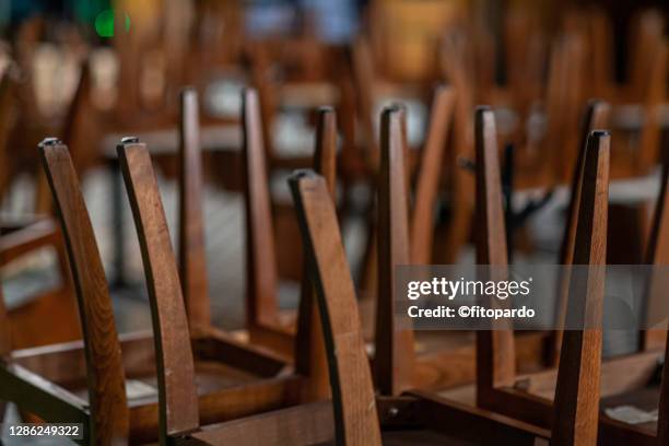 closed restaurant chairs turned over on tables - closing stockfoto's en -beelden